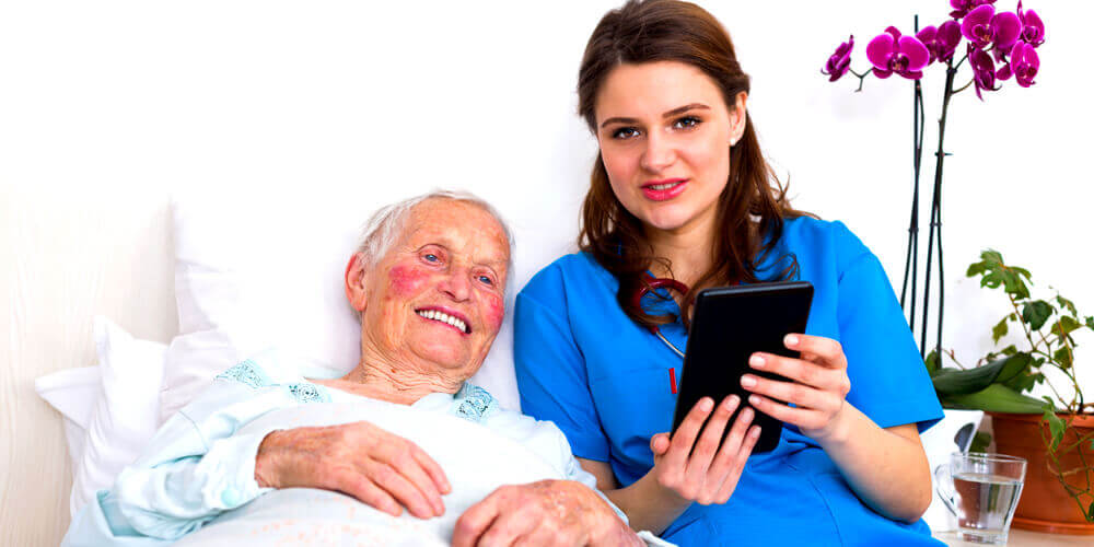 A nurse practitioner holds an elderly patient's hand in the hospital.