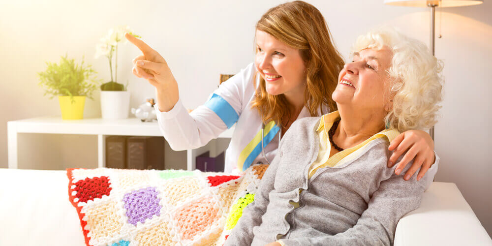 A caregiver interacts with a disabled care home resident.