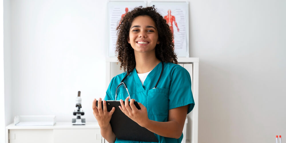 A nurse smiles as she poses for a photograph while holding a client file.
