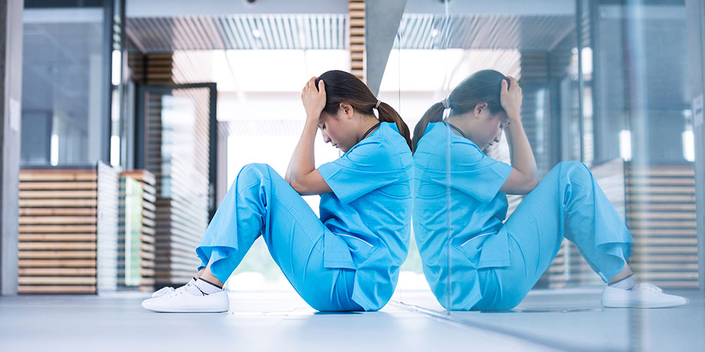 Two nurses and healthcare workers sitting exhausted after long shift hours
