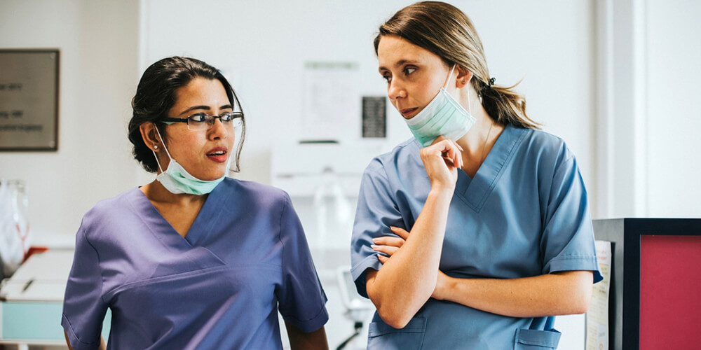 A professional nurse advocate converses with a nurse in an office.
