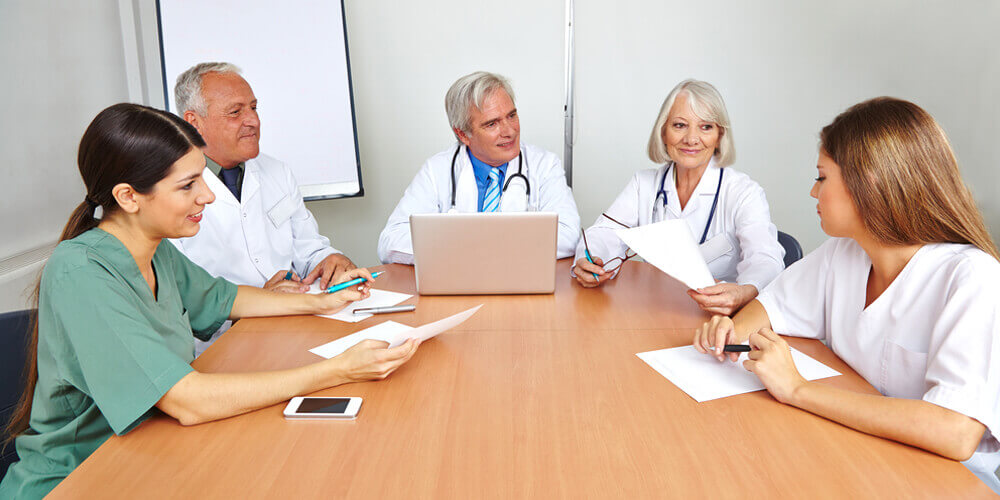 Nursing staff communicates with other care workers during a meeting.