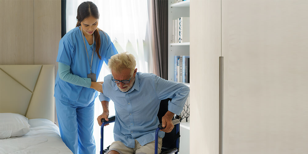 A support worker assists an elderly woman in a wheelchair at her home.