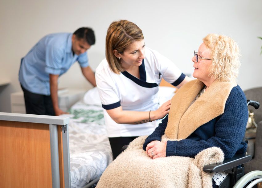 A nursing staff of a care facility assisting an elderly man and woman